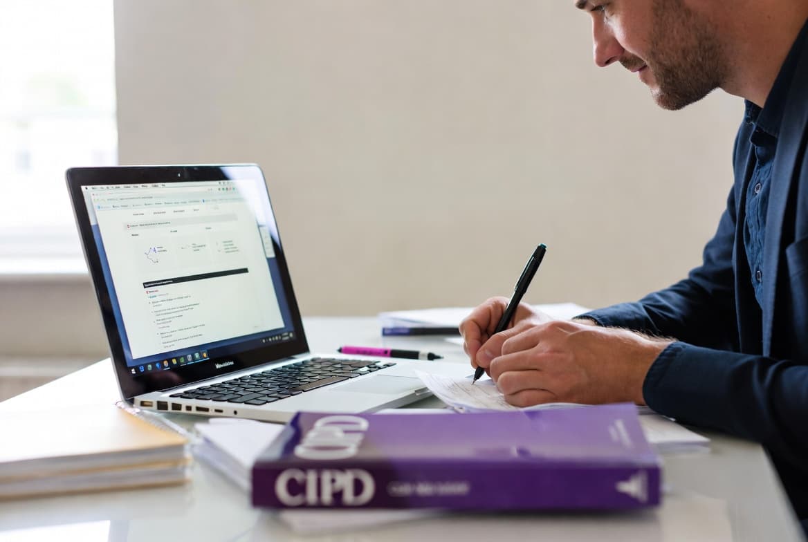 HR professional working on CIPD Level 5 assignment with laptop